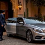 Chauffeur opening luxury sedan door at Moroccan riad