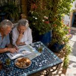 Senior couple relaxing at Moroccan café with travel guide